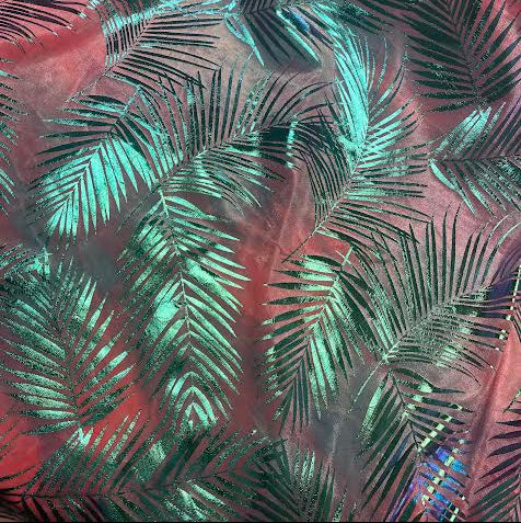 A close-up of a fabric or material surface with an allover tropical palm leaf pattern in metallic teal and dark green over a pinkish-red base.