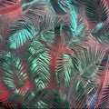 A close-up of a fabric or material surface with an allover tropical palm leaf pattern in metallic teal and dark green over a pinkish-red base.